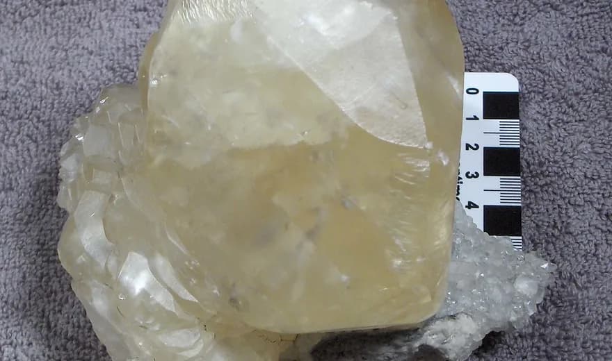 A large translucent calcite crystal photographed beside a measuring scale.