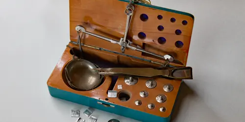 A cased jeweller’s balance with tweezers and a set of small carat weights.