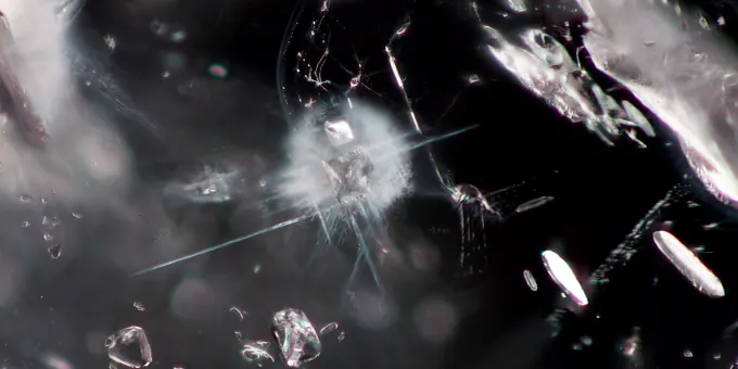 Inclusions inside a gemstone at magnification, needles and crystals scattered through the interior.
