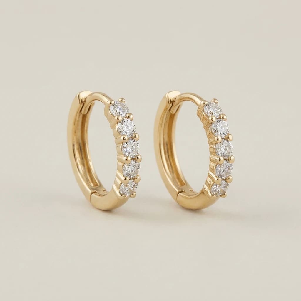 A pair of yellow gold hoop earrings, each set with a row of round diamonds.